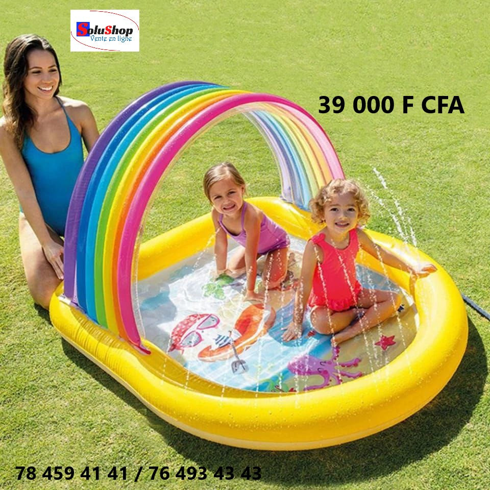 Enfant jouant sous l'arche arc-en-ciel de la piscine gonflable